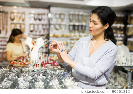 Asian woman looking for rings in costume jewelry showroom Asian woman looking for rings in costume jewelry showroom 90361813