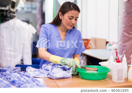 Focused woman drycleaner removing spots and stains Focused woman drycleaner removing spots and stains 90361895