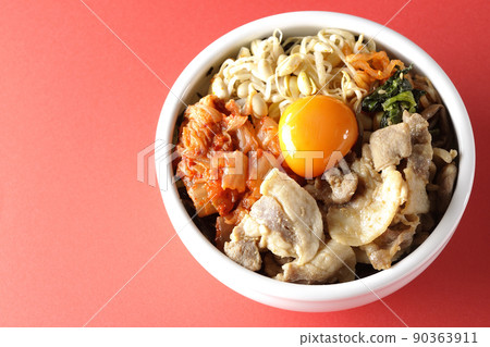 A bird's-eye view of the bibimbap bowl, which contains a lot of ingredients such as bean sprouts, kimchi, and pork. 90363911