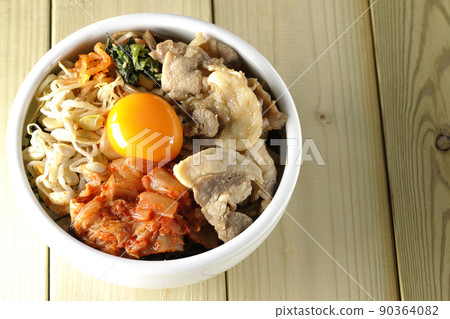 A bird's-eye view of the bibimbap bowl, which contains a lot of ingredients such as bean sprouts, kimchi, and pork. 90364082