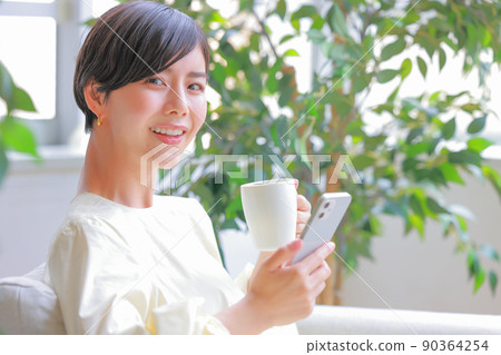 A woman who raised her face from her smartphone with a coffee cup in one hand 4 A woman who raised her face from her smartphone with a coffee cup in one hand 4 90364254