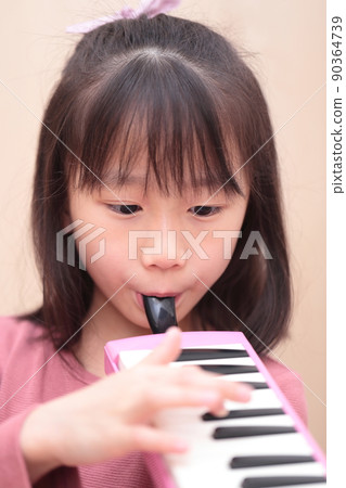Girl playing keyboard harmonica Girl playing keyboard harmonica 90364739