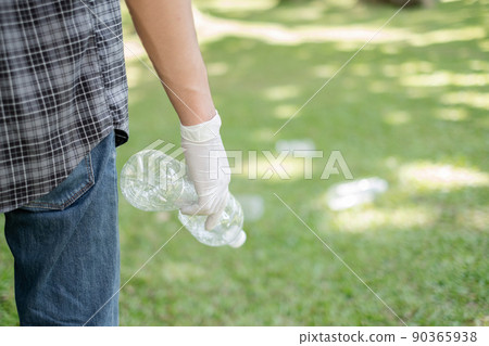 Garbage collection, Man's hands pick up plastic bottles, put garbage in black garbage bags to clean up at parks, avoid pollution, be friendly to the environment and ecosystem 90365938