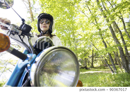 一個年輕的女人在湖邊騎著摩托車，一個摩托車女孩 90367017