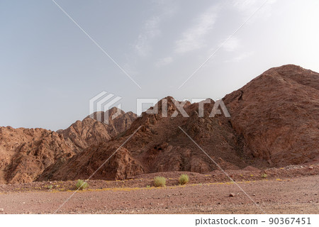 A road next to a mountainous desert landscape. Road 12 on the way to Eilat, Israel, on the Egyptian border. Mountains in different and varied sand colors. 90367451