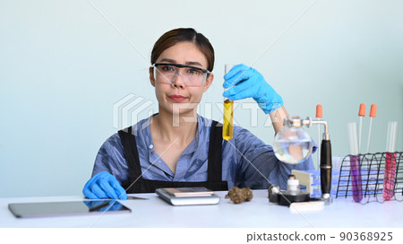 Female chemist holding test tube with marijuana natural aromatic hemp oil for research. Herbal alternative medicine, cbd oil concept Female chemist holding test tube with marijuana natural aromatic hemp oil for research. Herbal alternative medicine, cbd oil concept 90368925