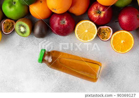 Various fruits and freshly squeezed fruits juice in bottle on gray background Various fruits and freshly squeezed fruits juice in bottle on gray background 90369127