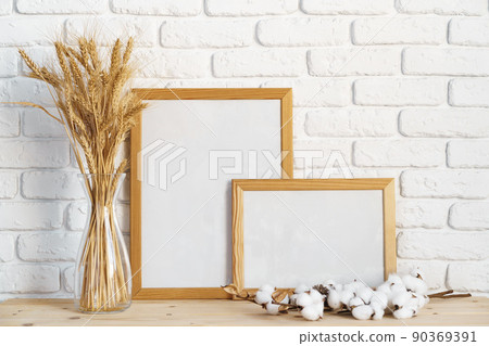 Vase with ears of wheat and photo frames against brick wall Vase with ears of wheat and photo frames against brick wall 90369391