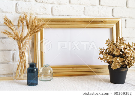 Mockup with a frame and dry flowers in a vase on a white table Mockup with a frame and dry flowers in a vase on a white table 90369392
