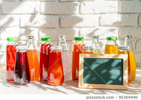 Glass bottles of different juices with picture frame copy space Glass bottles of different juices with picture frame copy space 90369490