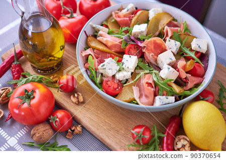 Salad with jamon or prosciutto, pears, tomatoes and arugula on wooden board 90370654