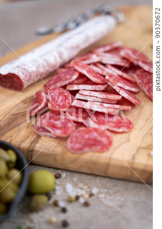 Sliced Spanish sausage fuet salami and vegetables on a domestic kitchen Sliced Spanish sausage fuet salami and vegetables on a domestic kitchen 90370672