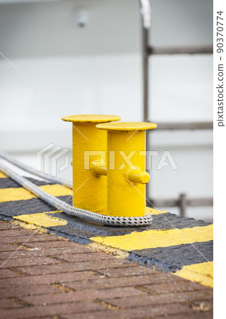 Thick rope and yellow bollards on wharf using for anchorage of yachts 90370774