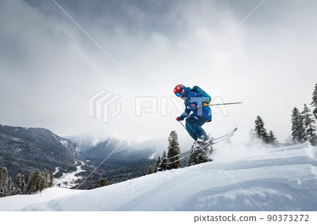 Freeride, a man is stylishly skiing on a snowy slope with snow dust plume behind him 90373272