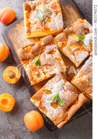 Prajitura cu caise is a traditional apricot cake originating from Romania closeup on the wooden board. Vertical top view Prajitura cu caise is a traditional apricot cake originating from Romania closeup on the wooden board. Vertical top view 90374072