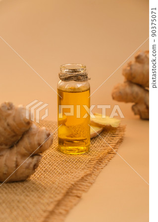 Glass bottle of essential ginger oil, ginger root on beige background. Healthy food eating concept. Zingiber officinale Essential oil. Natural cosmetics ingredients for skincare, body and hair care 90375071