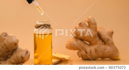 Glass bottle of essential ginger oil, ginger root on beige background. Healthy alternative living. Zingiber officinale Natural cosmetics ingredients for skincare, body and hair care 90375072