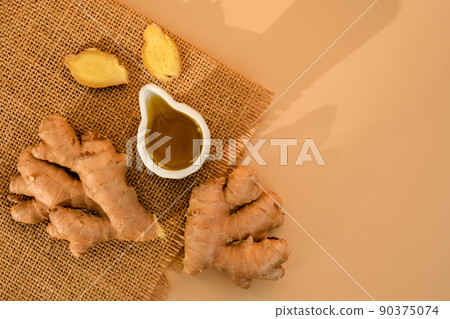 Sauce bowl of cooking ginger oil, ginger root on beige background. Healthy food eating concept. Zingiber officinale Natural cosmetics ingredients for skincare, body and hair care 90375074