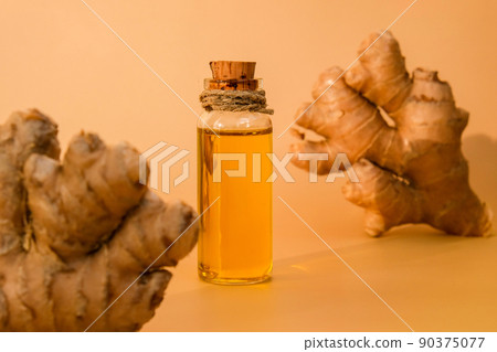 Glass bottle of essential ginger oil, ginger root on beige background. Healthy food eating concept. Zingiber officinale Essential oil. Natural cosmetics ingredients for skincare, body and hair care Glass bottle of essential ginger oil, ginger root on beige background. Healthy food eating concept. Zingiber officinale Essential oil. Natural cosmetics ingredients for skincare, body and hair care 90375077