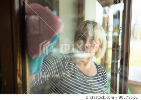 Woman hands in rubber gloves with a pink rag washes a window in the house or office, copy space. People, housework and housekeeping concept.  90375516