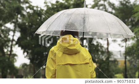 girl under umbrella. Slow motion. rain city park. view from back. young woman hiding under umbrella from raindrops. walk slush. rainfall rain. bad cloudy weather. man walks through wet streets park. 90375832