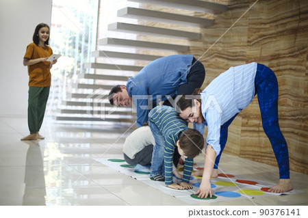 kids with father and mother playing twister game at home. Family activity kids with father and mother playing twister game at home. Family activity 90376141