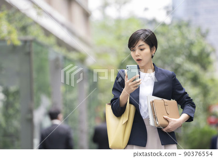 一位在智能手機上驚訝的女商人 90376554