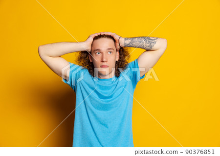 Young emotional man with long curly hair posing isolated on yellow background. Human emotions, facial expression concept. Trendy colors 90376851