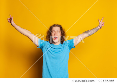 Young excited man with long curly hair posing isolated on yellow background. Human emotions, facial expression concept. Trendy colors 90376866