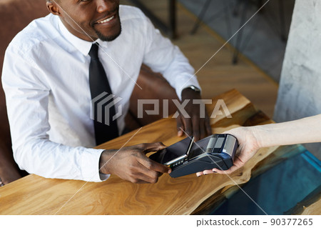 Close-up of smiling young black businessman in white shirt and necktie sitting at table paying for lunch in restaurant Close-up of smiling young black businessman in white shirt and necktie sitting at table paying for lunch in restaurant 90377265
