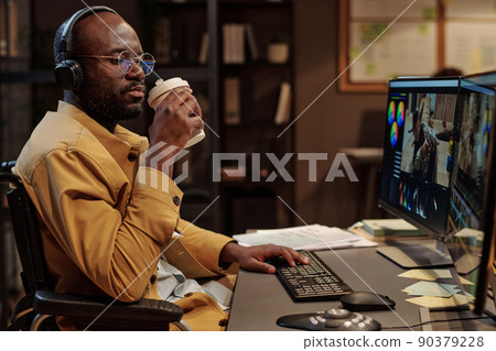 African colorist in headphones with disability drinking coffee during break at his workplace at office African colorist in headphones with disability drinking coffee during break at his workplace at office 90379228