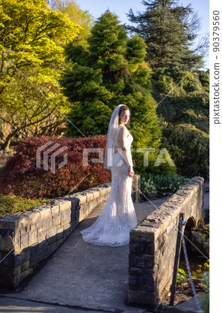 White Caucasian Adult Woman in a Wedding Dress standing outside in nature. White Caucasian Adult Woman in a Wedding Dress standing outside in nature. 90379560