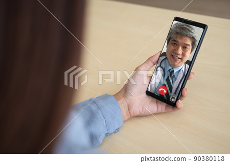 Asian doctor or therapist help relieve stress and provide knowledge and understanding about office syndrome to patients video conference call online live talk remotely at home by smartphone Asian doctor or therapist help relieve stress and provide knowledge and understanding about office syndrome to patients video conference call online live talk remotely at home by smartphone 90380118