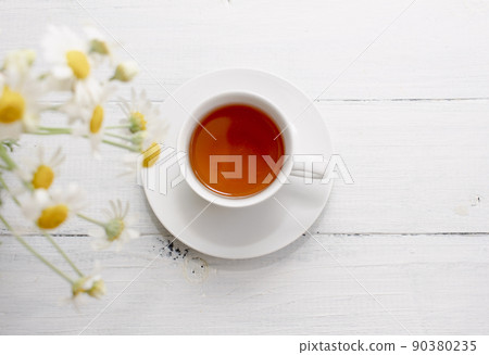 Chamomile flowers and white cup of tea. Alternative tea and medicine concept. Chamomile flowers and white cup of tea. Alternative tea and medicine concept. 90380235
