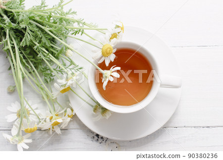 Chamomile flowers and white cup of tea. Alternative tea and medicine concept. Chamomile flowers and white cup of tea. Alternative tea and medicine concept. 90380236