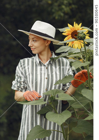 Young woman with sunflowers. Lady in a hat. Girl in a garden. Young woman with sunflowers. Lady in a hat. Girl in a garden. 90380645
