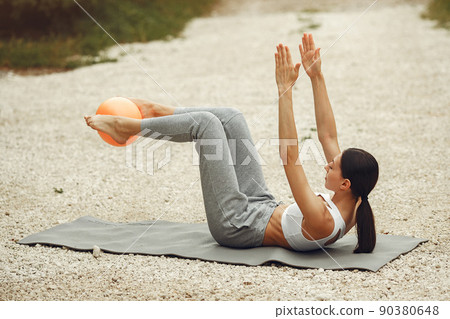 Pretty lady training on a summer beach. Brunette doing yoga. Girl in a sportsuit. Pretty lady training on a summer beach. Brunette doing yoga. Girl in a sportsuit. 90380648