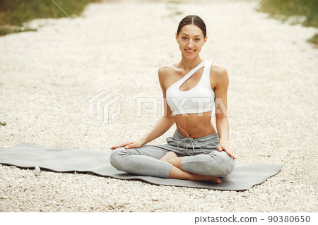 Pretty lady training on a summer beach. Brunette doing yoga. Girl in a sportsuit. Pretty lady training on a summer beach. Brunette doing yoga. Girl in a sportsuit. 90380650