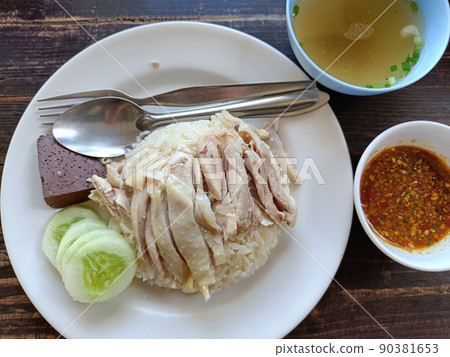 Hainanese chicken rice eat with chicken soup and sauce on a wooden background Hainanese chicken rice eat with chicken soup and sauce on a wooden background 90381653