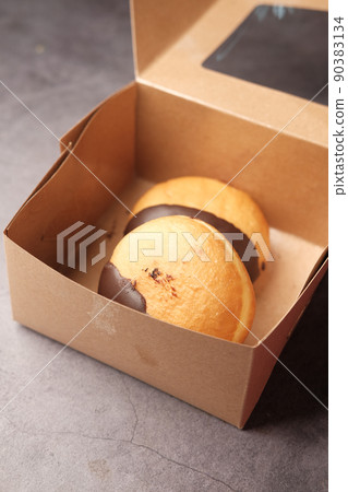chocolate donuts in a paper packet on table chocolate donuts in a paper packet on table 90383134