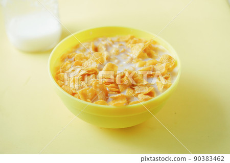 corn flakes and milk in a yellow color bowl corn flakes and milk in a yellow color bowl 90383462
