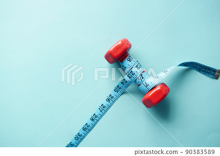 Fitness concept with dumbbell and measurement tape on table  90383589