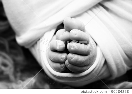 The tiny foot of a newborn. Soft feet of a newborn in a blanket. Close up of toes, heels and feet of a newborn baby. Studio Macro photography. Woman's happiness. Concept. Black and white. 90384228