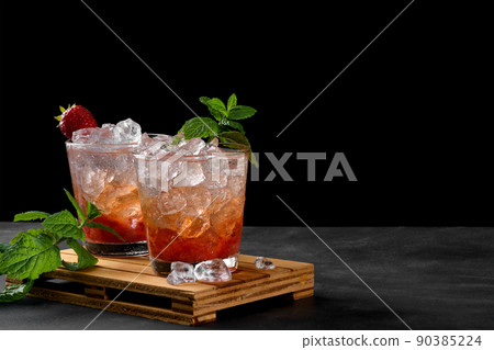 Cold summer strawberry iced cocktail mojito, margarita, daiquiri in two glasses with mint leaves on dark background Cold summer strawberry iced cocktail mojito, margarita, daiquiri in two glasses with mint leaves on dark background 90385224