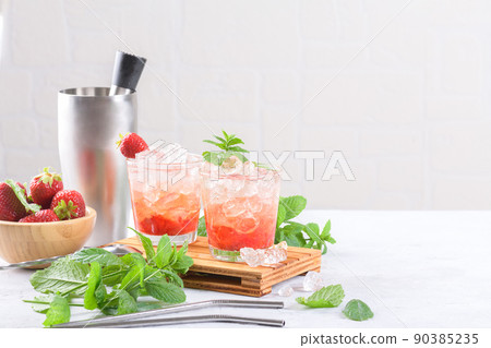 Cold strawberry cocktail mojito, margarita, daiquiri in two glasses with mint, ice and bartender tools on light table Cold strawberry cocktail mojito, margarita, daiquiri in two glasses with mint, ice and bartender tools on light table 90385235