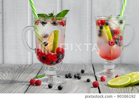 Fresh homemade summer cocktails with ice, lime and berries in glasses with a straw 90386192