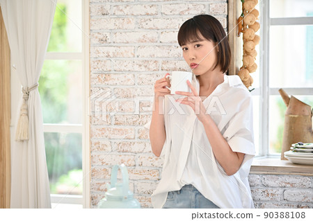 年輕女子在廚房的杯子裡喝飲料 年輕女子在廚房的杯子裡喝飲料 90388108
