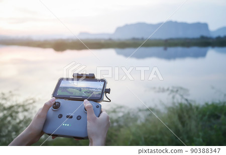 hands using drone command radio for flying in evening time to take high view photo 90388347