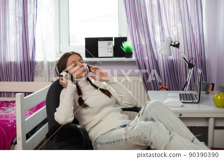 The teenager closed her eyes and listens focused to the music on her headphones. The teenager closed her eyes and listens focused to the music on her headphones. 90390390