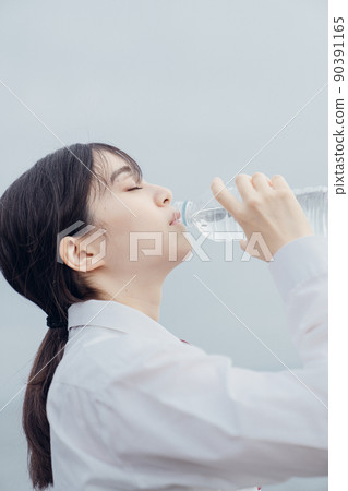 High school girl drinking water at the beach High school girl drinking water at the beach 90391165
